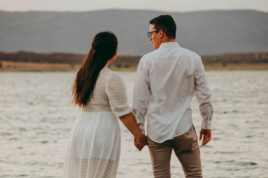 Un couple se tenant la main face à un lac, symbolisant l'harmonie et l'équilibre de la libido au sein du couple.